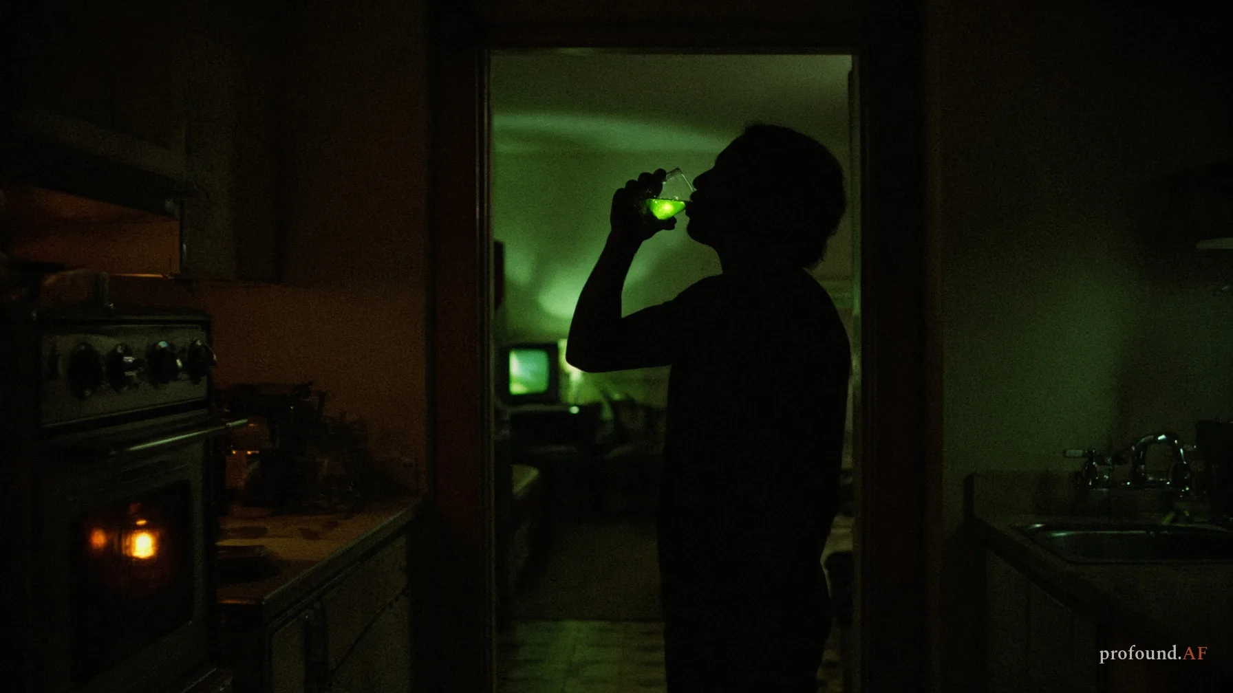 A silhouetted person drinks a glass of water that glows green in the light of a television in the next room.